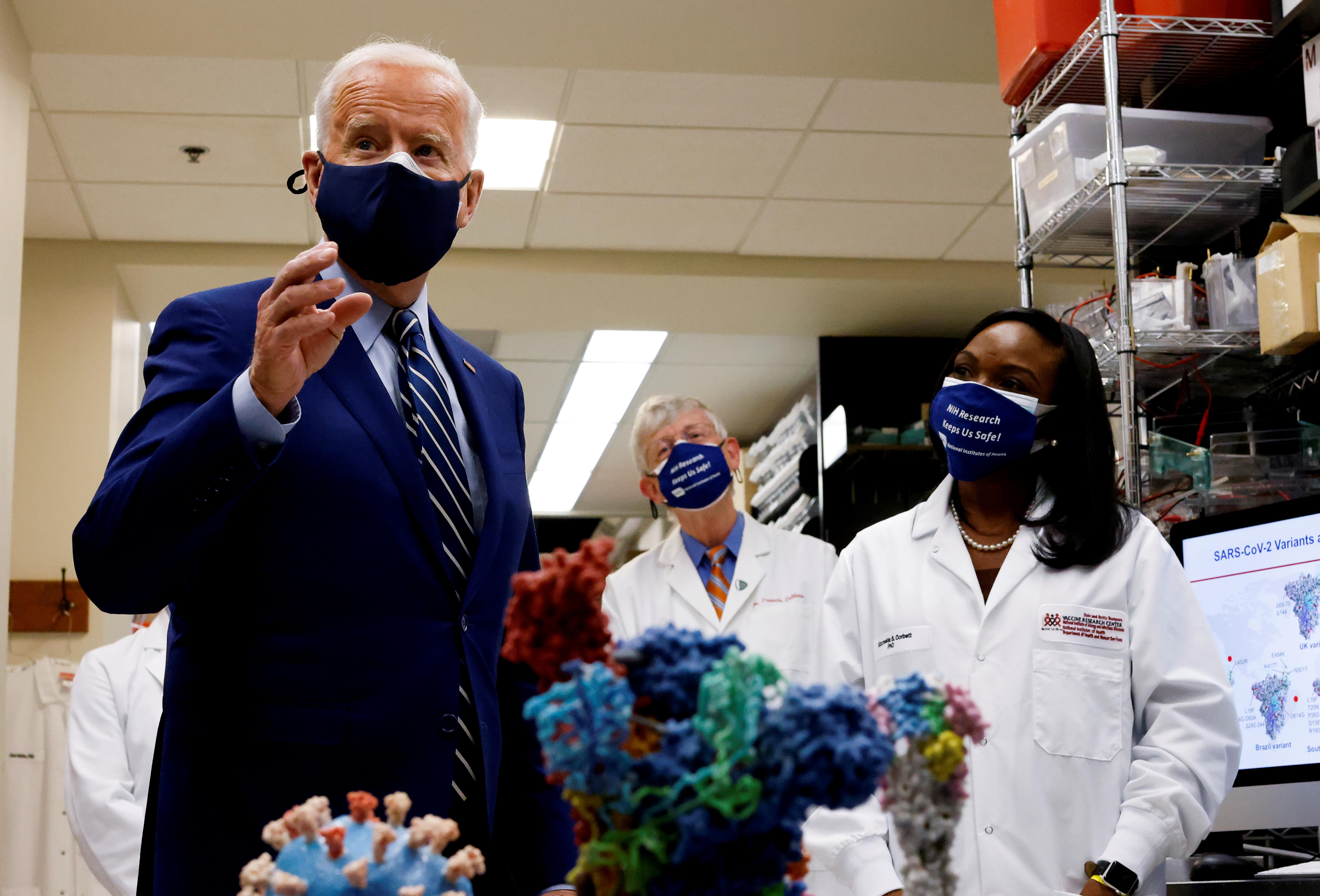 U.S. President Joe Biden speaks next to an NIH staff member as NIH Director Francis Collins listens during a visit to the Viral Pathogenesis Laboratory at the National Institutes of Health (NIH) in Bethesda, Maryland, U.S., February 11, 2021.